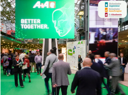Messebesucher auf der A+A Fachmesse für Arbeitsschutz und Sicherheit, großer grüner Bildschirm mit Schriftzug 'BETTER TOGETHER' und A+A Logo