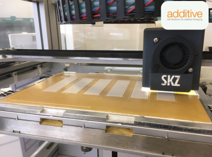 3D-Drucker mit SKZ-Beschriftung druckt rechteckige Objekte auf einer flachen Bauplattform