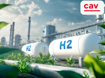 Zwei große, weiße Wasserstofftanks mit der Aufschrift 'H2' stehen in einer Industrieanlage, umgeben von grünen Pflanzen. Im Hintergrund sind weitere Industriegebäude und Rohre sichtbar. Das Logo 'cav' ist oben rechts.
